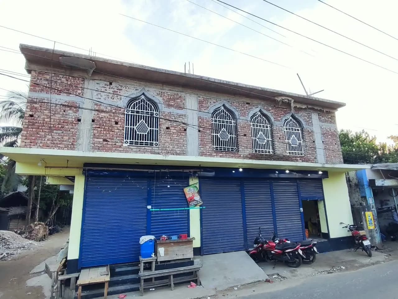 রাস্তার দিক থেকে দেখা অসমাপ্ত উপরতলা ও ফ্যাকাশে হলুদ নিচতলার সামনের অংশ