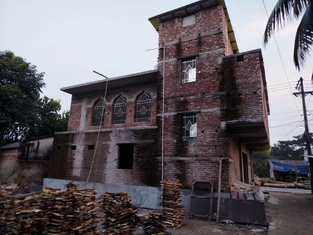 মসজিদের পাশের বাইরের দৃশ্য — উন্মুক্ত ইট, খিলানযুক্ত জানালা ও টাওয়ার